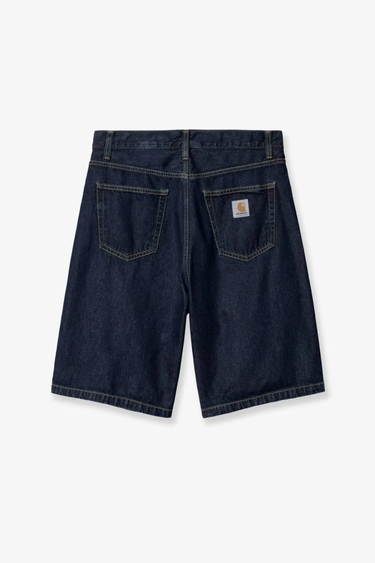 Back side of dark indigo denim bermuda shorts with classic carhartt logo patch on the back right pocket