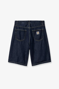 Back side of dark indigo denim bermuda shorts with classic carhartt logo patch on the back right pocket