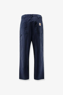 Back view of dark navy blue carhartt wip men’s loose fit denim jeans with multiple pockets and logo patch