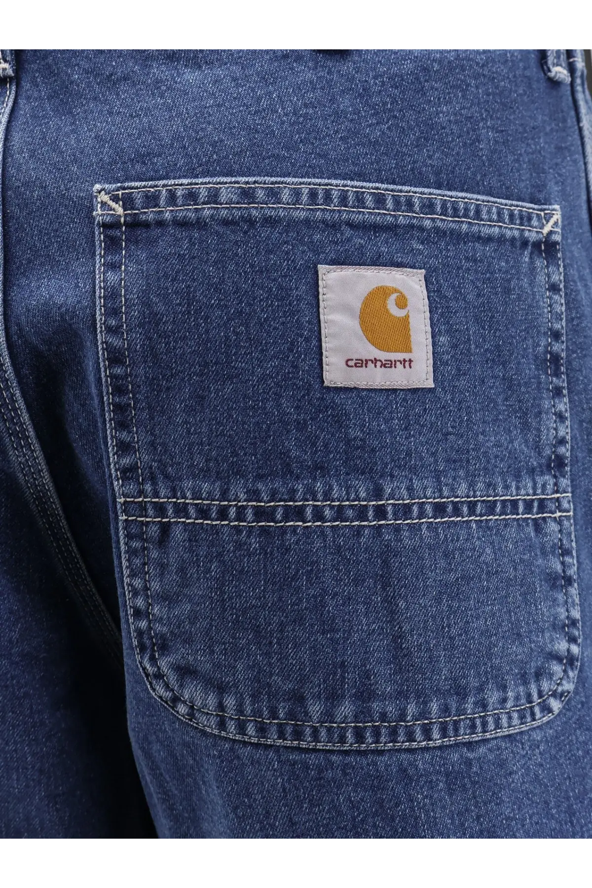 Back side of blue denim carhartt wip men’s norco relaxed straight fit jeans with white patch and orange logo on pocket