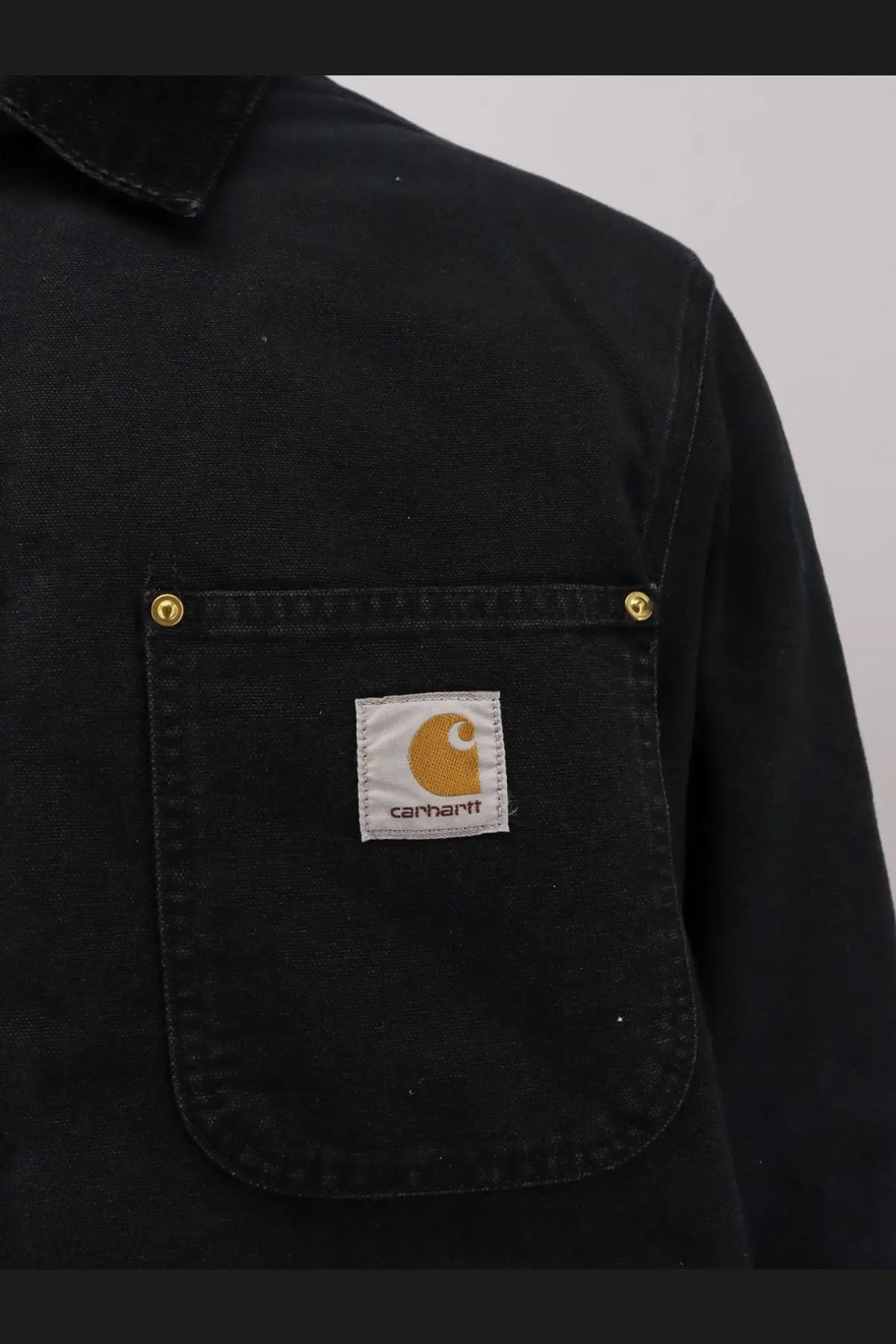Black Carhartt Wip men’s OG chore coat padded jacket with chest pocket gold rivets and orange logo patch organic cotton