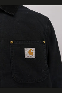 Black Carhartt Wip men’s OG chore coat padded jacket with chest pocket gold rivets and orange logo patch organic cotton