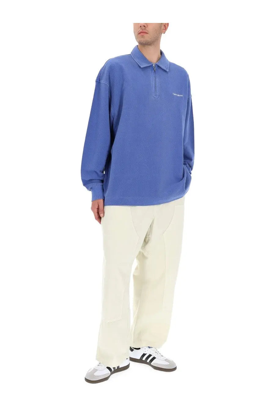 Blue carhartt polo shirt with half-zip front and white logo paired with carhartt wip men’s pants crawton white