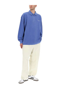 Blue carhartt polo shirt with half-zip front and white logo paired with carhartt wip men’s pants crawton white