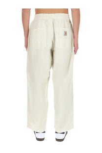 Back view of cream-colored carhartt wip men’s relaxed-fit cargo pants with elastic waistband and logo patch