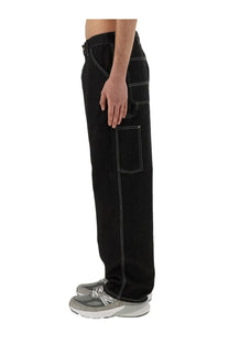Carhartt Wip men’s single knee black denim pants with white stitching and multiple pockets for durability and utility