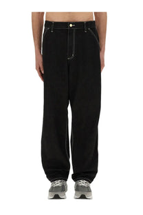 Carhartt WIP men’s black single knee wide-leg denim pants with white stitching and yellow button detail