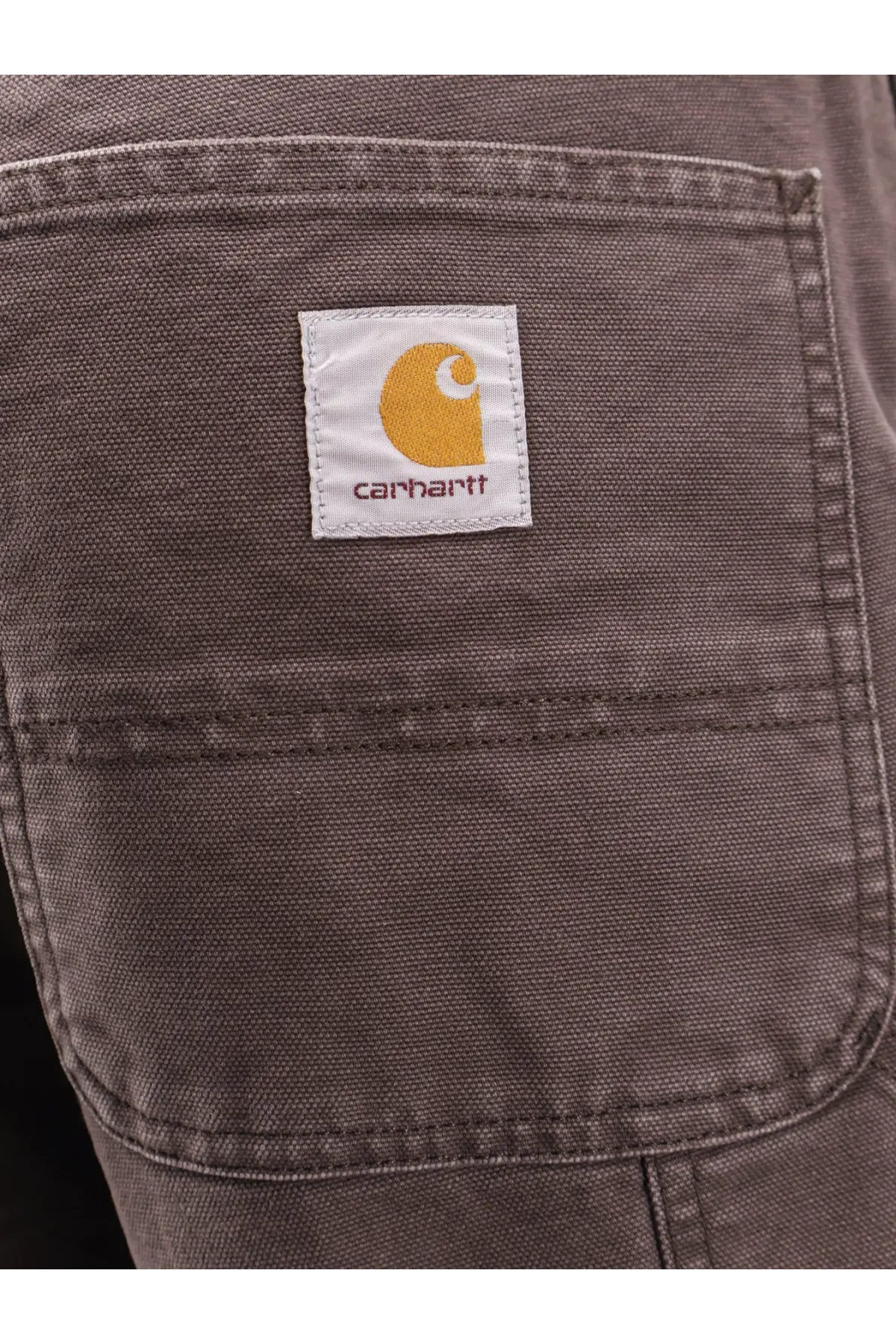 Dark gray carhartt wip men’s single knee pant jeans pocket with white label featuring orange logo and maroon carhartt text