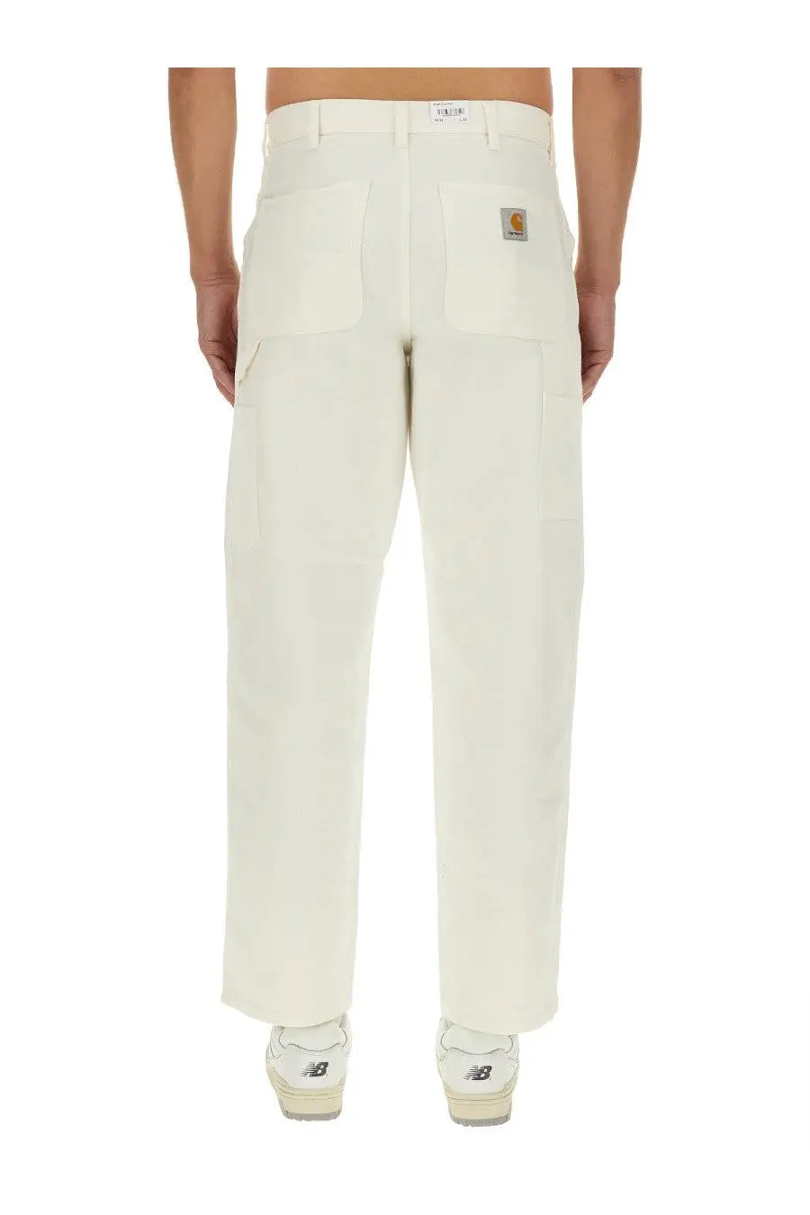 Cream-colored carhartt wip men’s single knee cargo pants with sturdy utilitarian design and brand patch on back pocket
