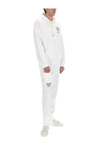 Casablanca men’s jogger pants tennis club icon white paired with a white hooded sweatshirt with a neon yellow zipper pull