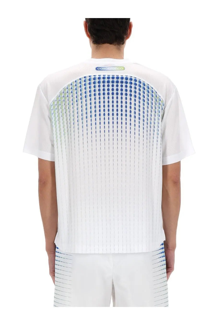 Back side of Casablanca men’s white short-sleeved shirt with gradient blue dot pattern, vertical pleats, and subtle cosmic logo
