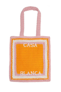 A pink and orange crocheted unisex tote bag with casa blanca embroidered in white on the front