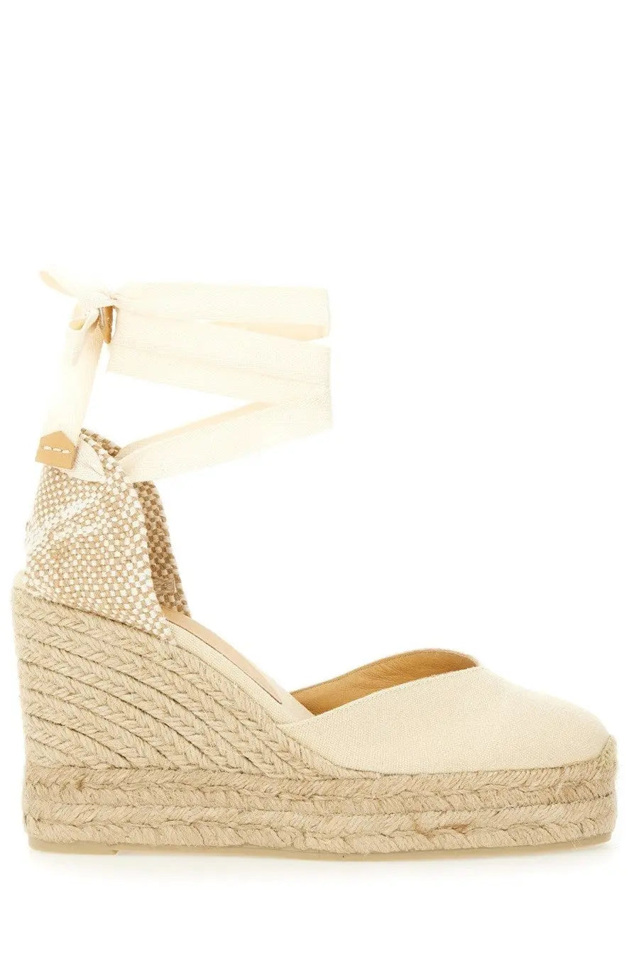 Cream-colored Castañer women’s espadrille wedge sandal with woven jute sole fabric upper and ankle strap tied in a bow