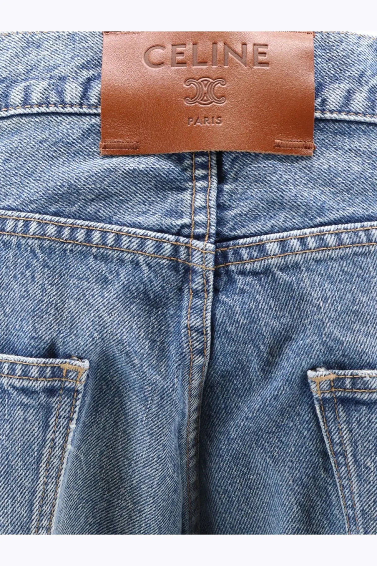 Blue denim celine men’s boyfriend jeans with brown leather celine paris brand label at the waistband back view
