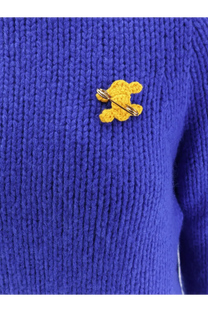 A yellow crocheted teddy bear pin with metallic clasp attached to a celine women’s blue cashmere and silk blend sweater