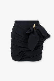 Celine women’s black ruched draped mini skirt with gold circular buckle and fabric bow detail for stylish wear