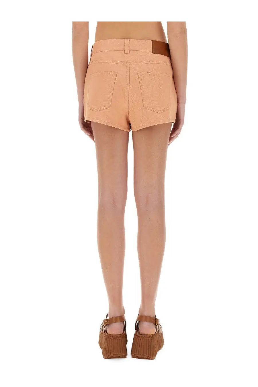 Beige high-waisted cotton denim shorts with brown leather belt loop and back pockets shown from the back side
