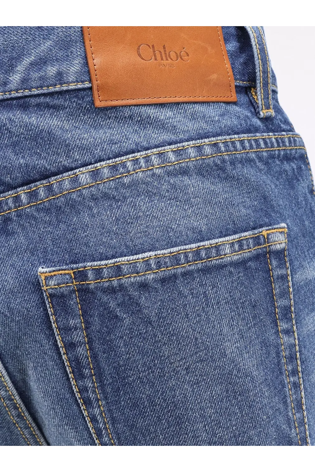 Blue denim jeans with a tan leather chloé paris patch on the back for women
