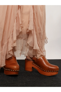 Brown leather clog shoes with a chunky wooden heel and metallic studs along the sole.