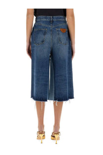 Back side of chloé women’s blue denim culottes with frayed hem and brown leather patch on the back pocket