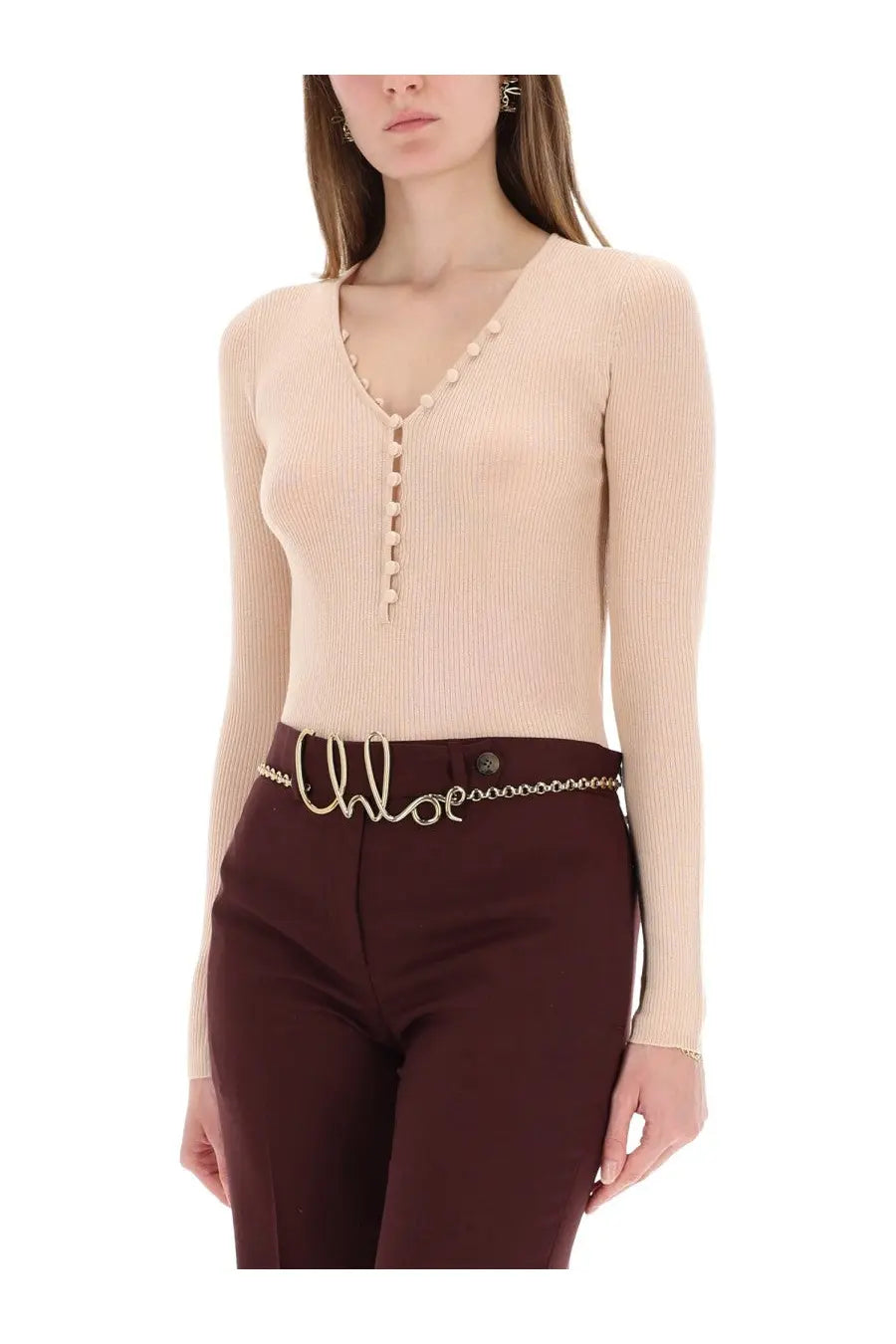 A gold-tone chain belt with the brand name chloé in cursive worn around the waist paired with a blue ribbed knit