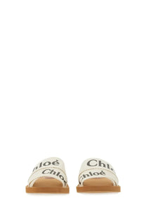 Cream-colored canvas slide sandals with black chloé branding on straps from chloé women’s sandal woody white collection
