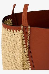 A tan woven straw and brown leather Chloé tote bag with gold chain strap and Chloé Paris logo charm