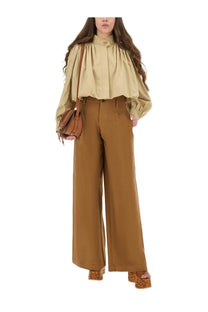 Tan leather crossbody bag with structured rounded shape and adjustable strap paired with chloé women’s brown wide leg pants