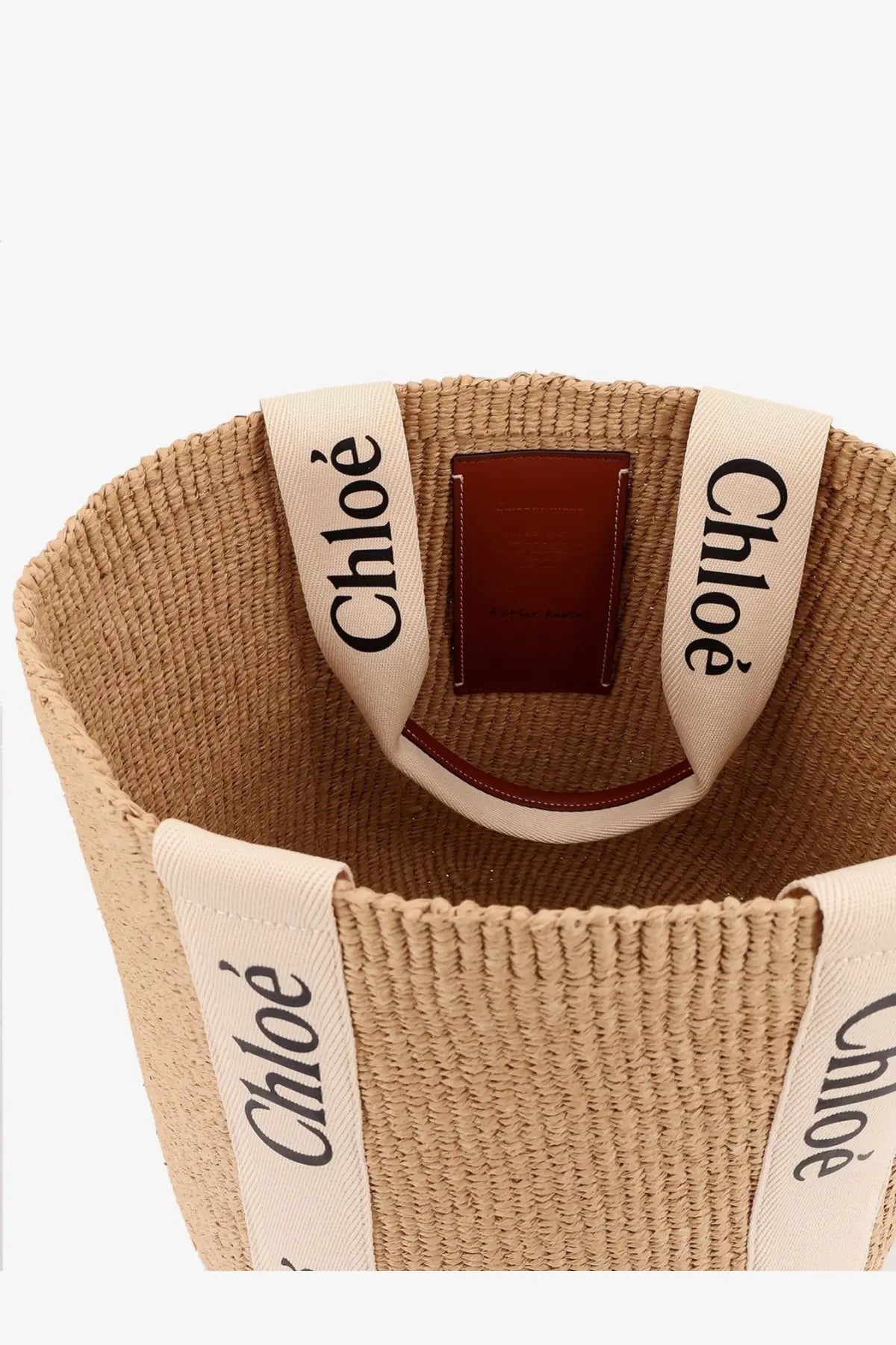 Beige woven straw chloé womens woody raffia shoulder bag with cream fabric handles and brown leather patch