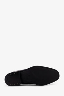 Back side of Church’s men’s Consul leather lace black shoe showing black leather sole with stitched edges and metallic studs