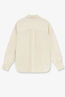 Cream-colored closed women’s cropped silk shirt with long sleeves and subtle back pleats shown from the back side