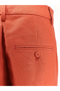 A pair of closed women’s jurdy cotton and linen rust-colored trousers with textured fabric and a buttoned flap pocket