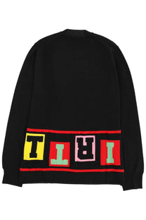 Back of black comme des garcons knit men’s sweater with bold colorful tiri lettering in yellow red and mint green blocks