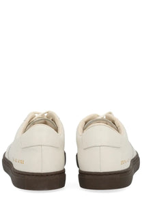 Common projects men’s bball slim sneaker white cream leather with dark brown rubber soles and gold-tone heel branding back view