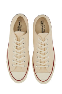 Cream-colored canvas converse unisex chuck sneaker with red rubber sole trim and white toe cap