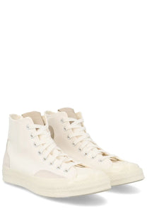 Cream-colored unisex Converse Chuck high-top sneakers with canvas upper, rubber sole, white laces, and metallic eyelets