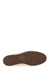 Brown rubber sole with classic diamond tread and white stitching on a beige Converse unisex Chuck vintage sneaker
