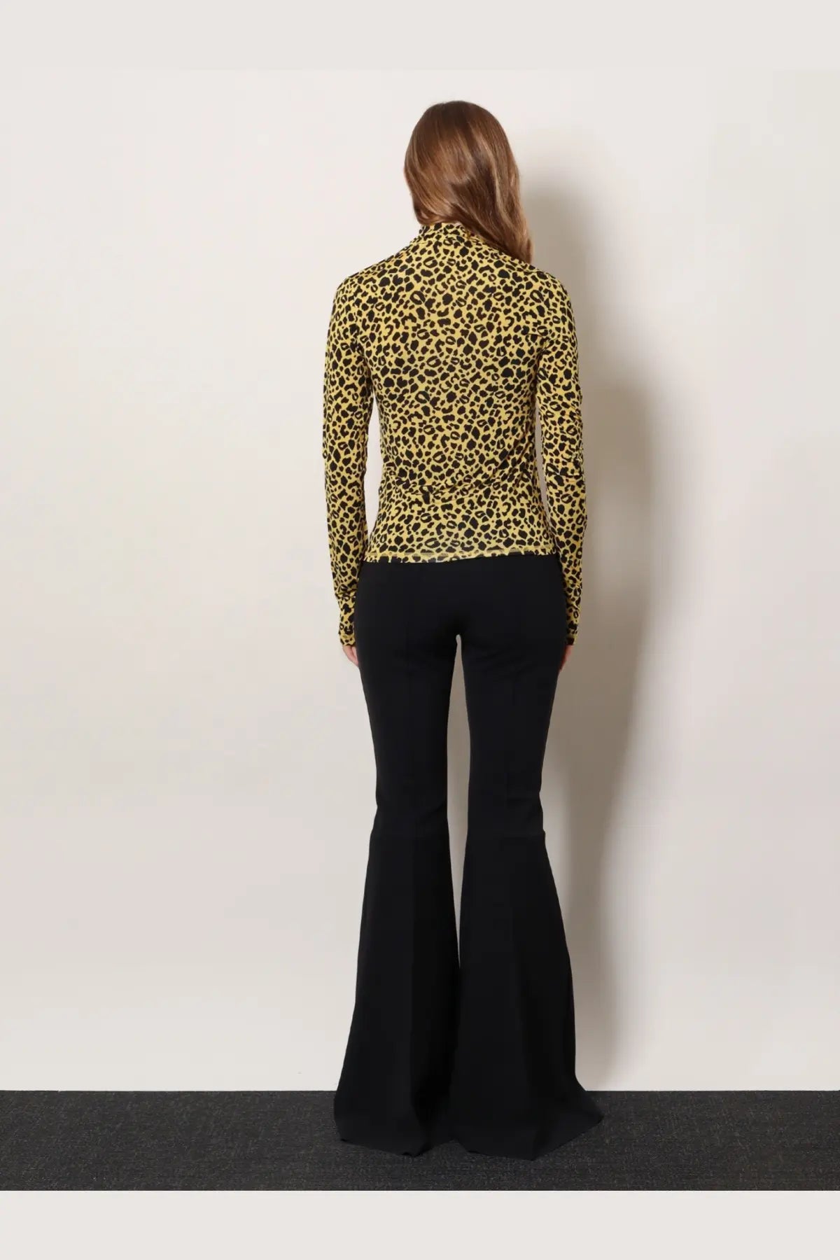 A woman wearing a long-sleeved leopard-print knitted viscose top from Coperni paired with black flared pants
