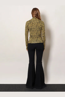 A woman wearing a long-sleeved leopard-print knitted viscose top from Coperni paired with black flared pants
