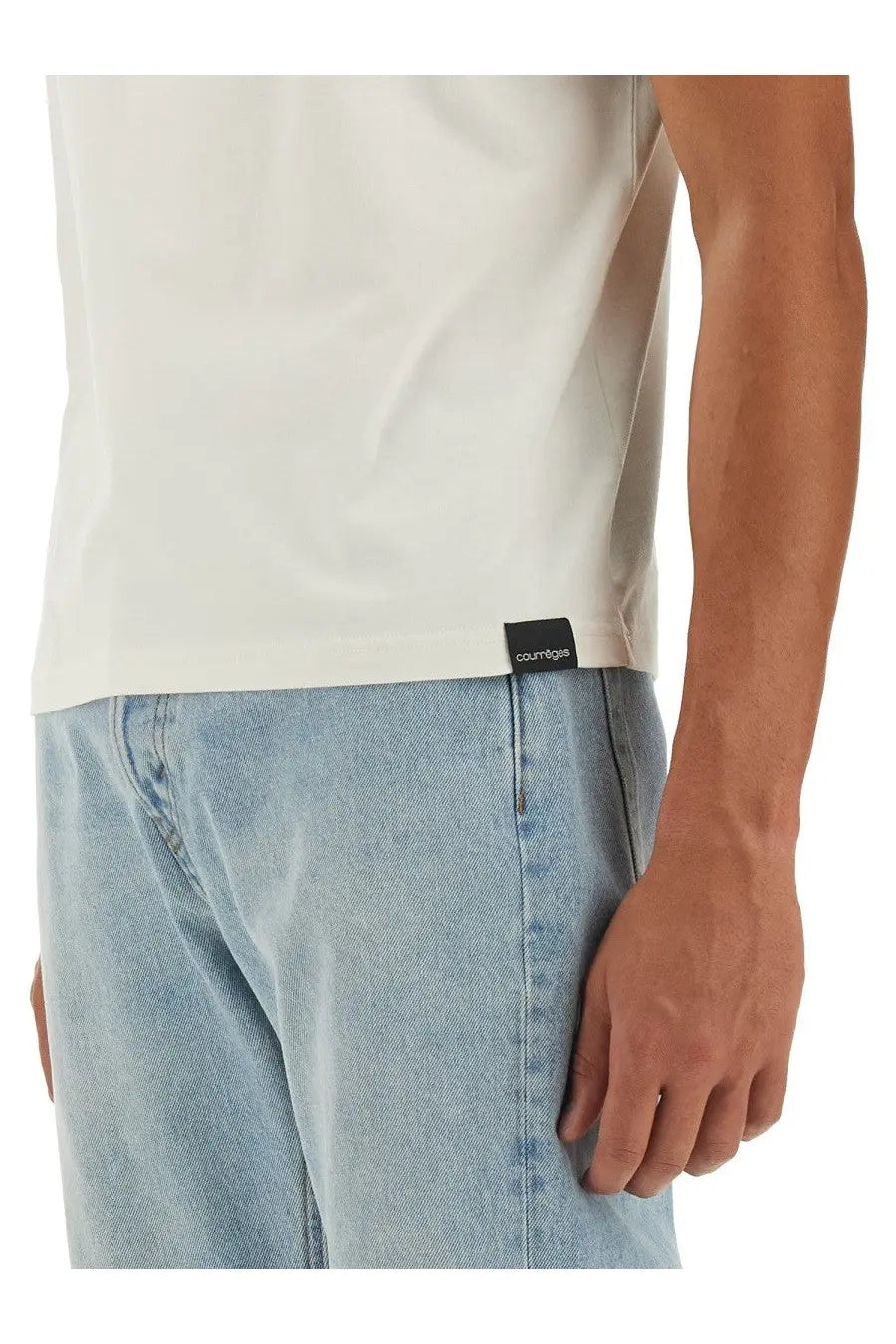Cream-colored courrèges men’s cotton t-shirt with a black brand tag at the hem showing the front side
