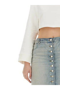 Light-wash denim skirt with a vertical row of white buttons down the front paired with courrèges white cropped sweatshirt