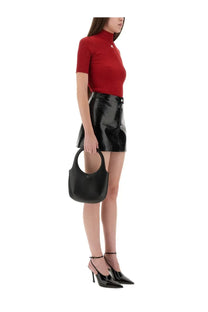 Black patent leather hobo bag with circular top handle and minimalist logo detail paired with courrèges vinyl mini skirt