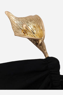 Golden calla lily-shaped metal accessory with intricate veining on a black viscose blend long dress by cult gaia