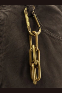 Darkpark men’s brown cotton trousers feature a brass-colored thick-link chain with a carabiner clip attached