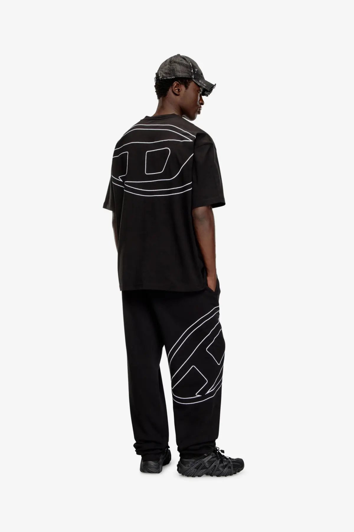 Back view of diesel men’s boggy black cotton t shirt with bold white geometric line art on back and side of pants