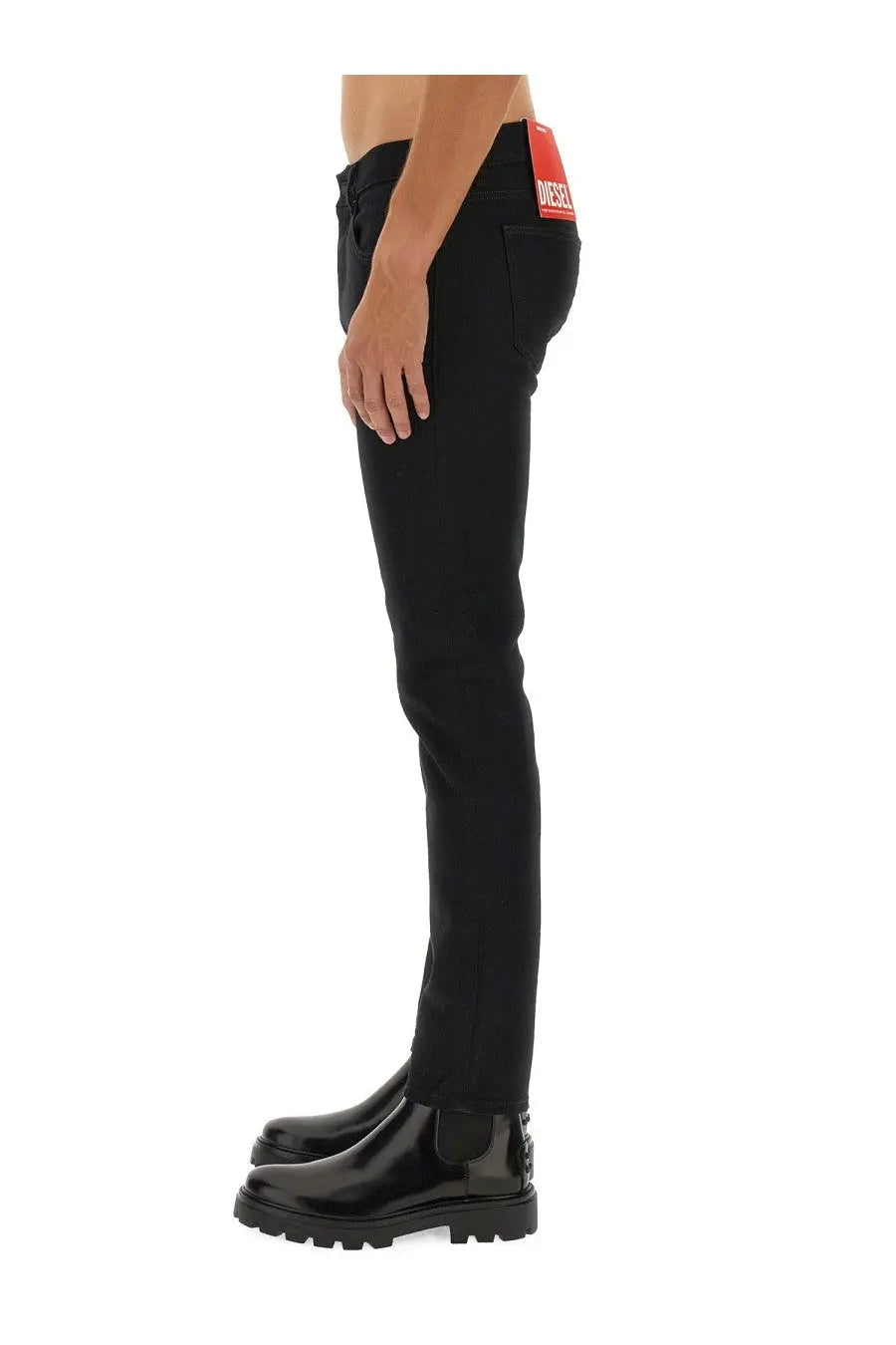 Back view of diesel men’s strukt black slim fit jeans with a red brand tag on the waistband