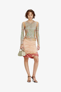 A delicate light green and peach floral-patterned long-sleeved top with sheer overlay paired with diesel dome python leather beige crossbody bag