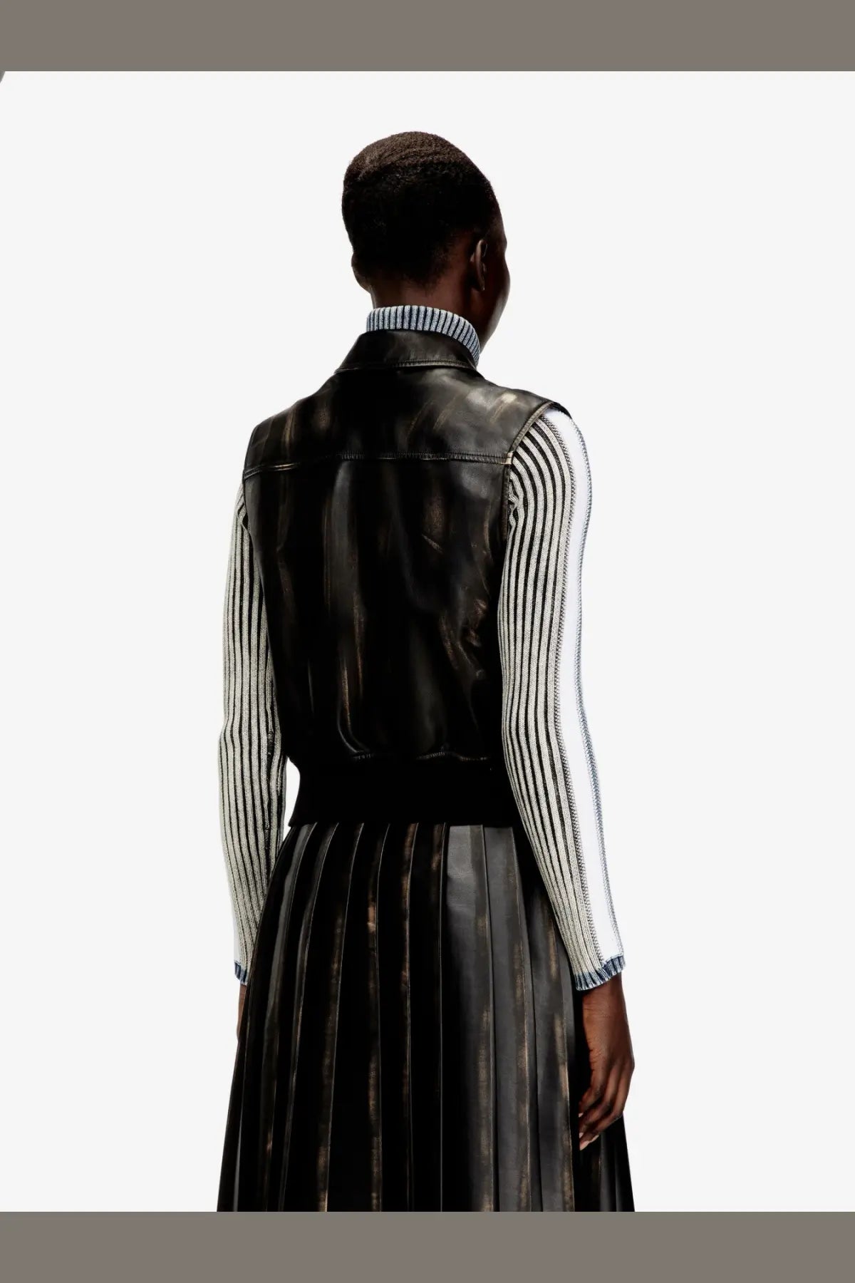 Diesel women’s Inko black faux leather sleeveless jacket with vertical stitching and high collar worn over striped shirt