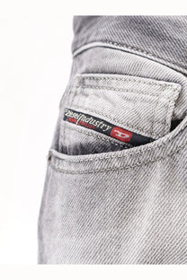 Gray denim jeans with black and red diesel industry label featuring white text on the back side