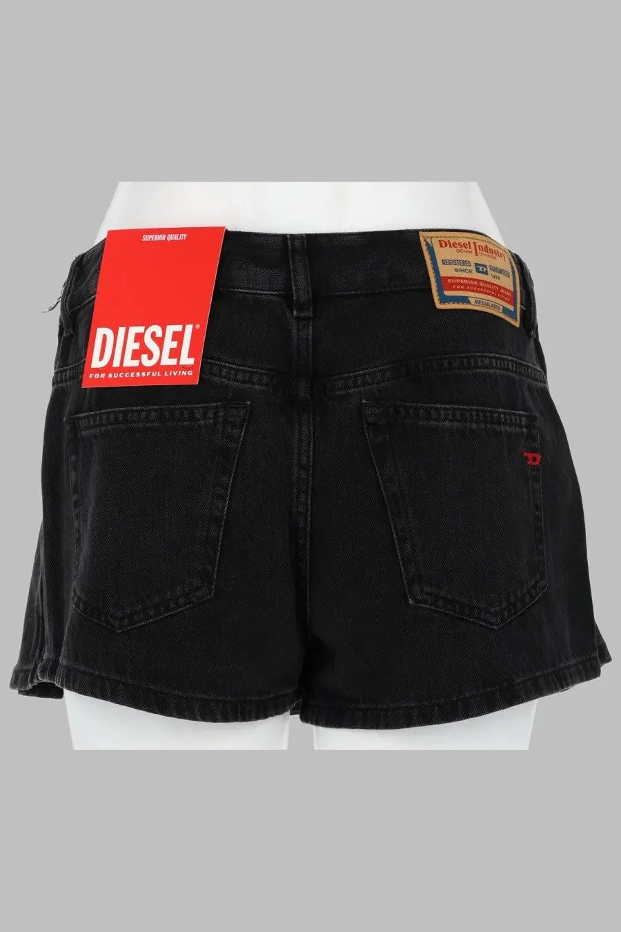 Back view of diesel women’s skort pieghe in black denim with red diesel tag and brown leather patch on waistband